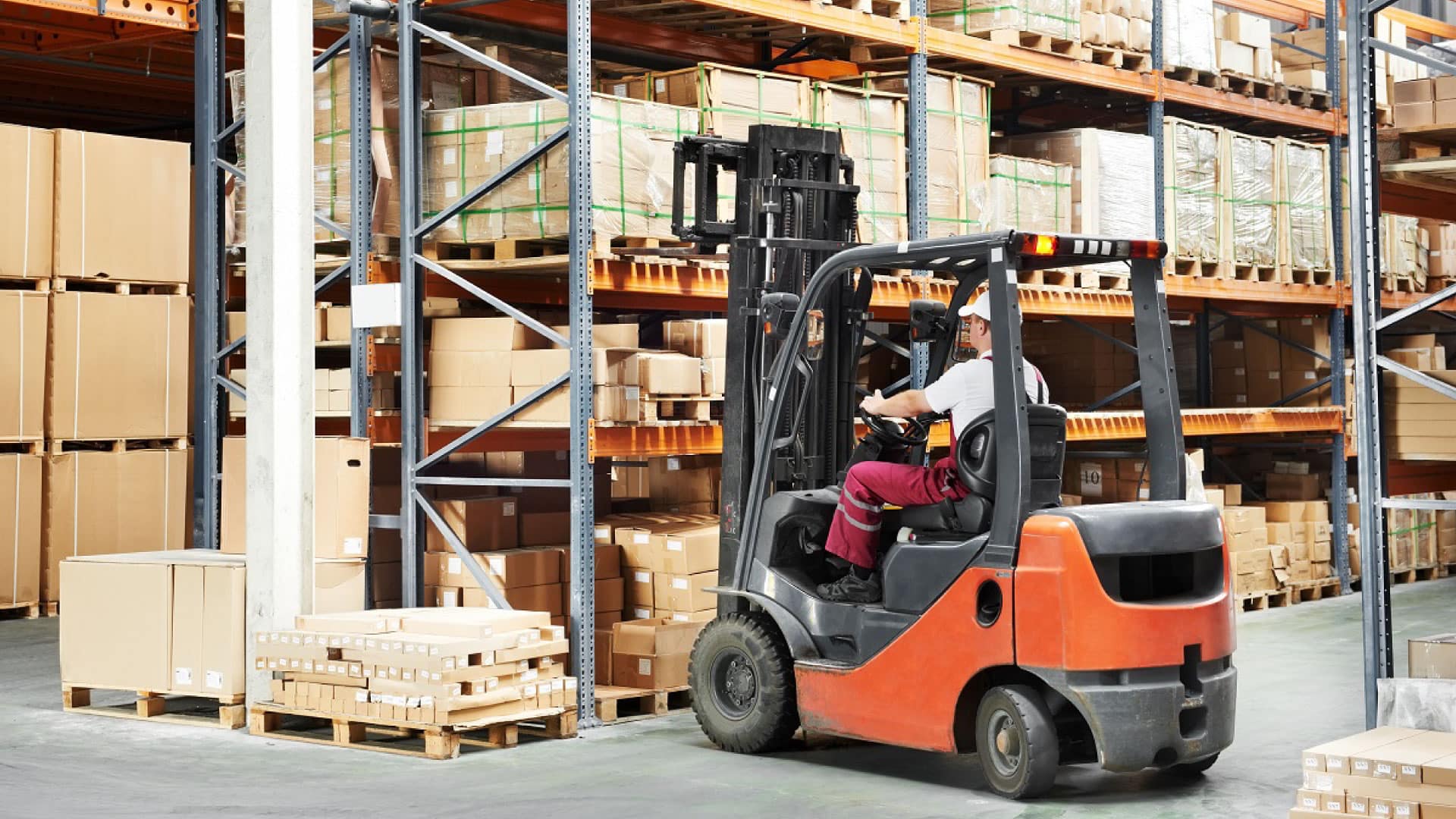 Warehouse worker operating a forklift while organizing pallets, representing Optimizing Warehouse Operations with efficient equipment and skilled operators.