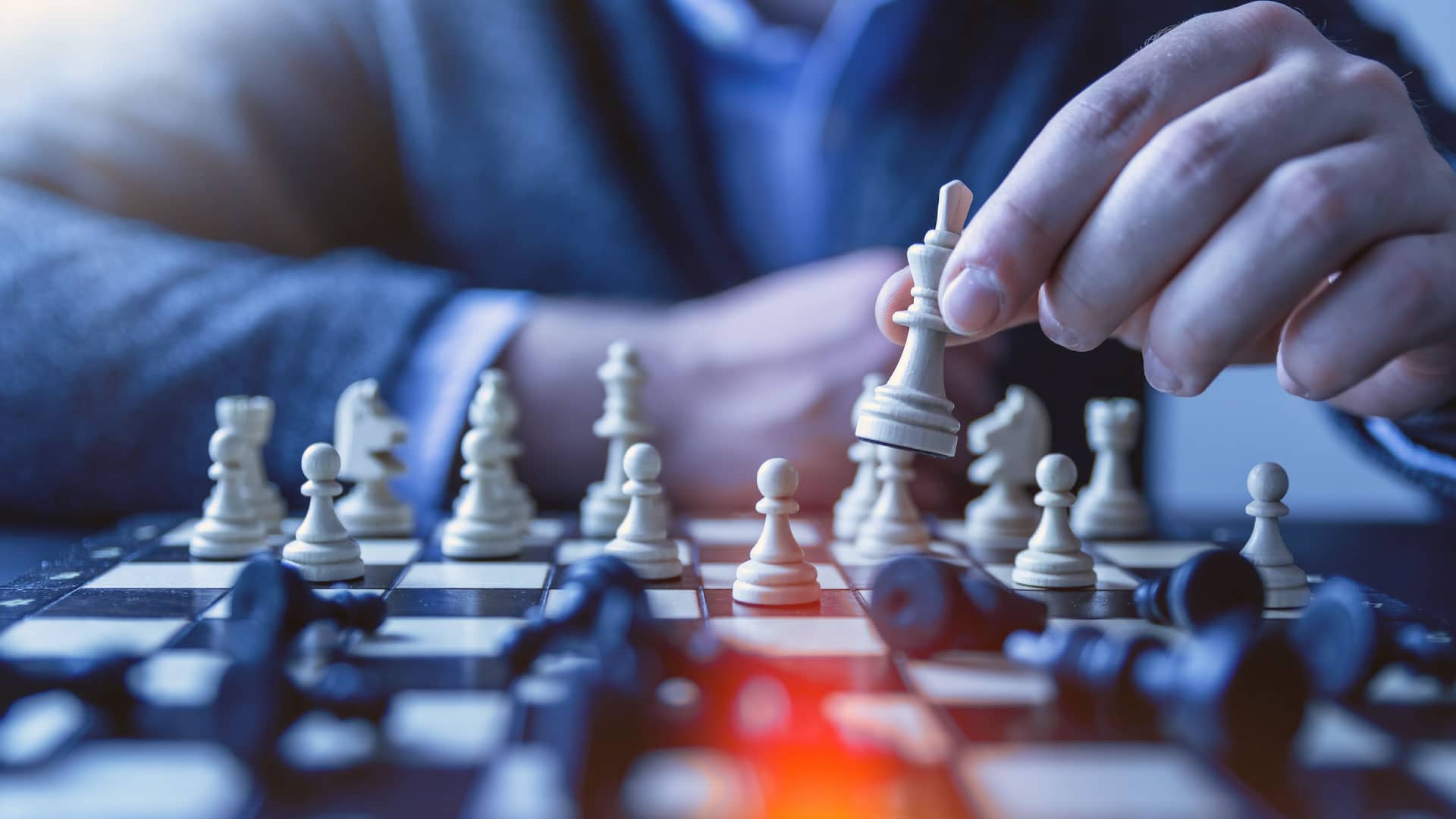 Man playing chess, taking the queen with his right hand