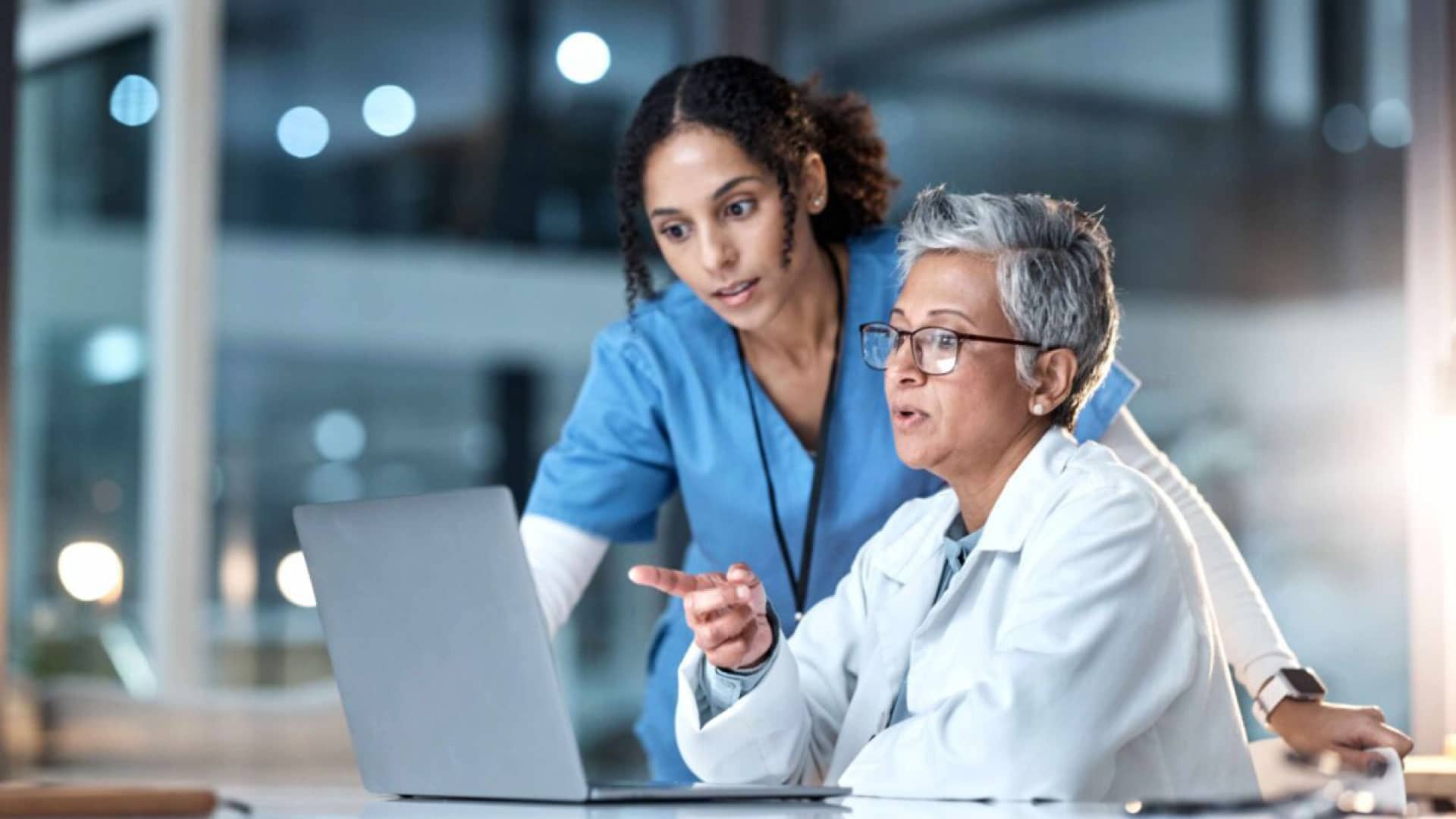 Two doctors discussing patient safety in healthcare while reviewing data on a laptop, fostering a safety culture in healthcare.